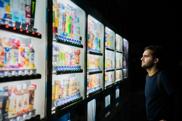Man standing in front of a vending machine, pondering his options