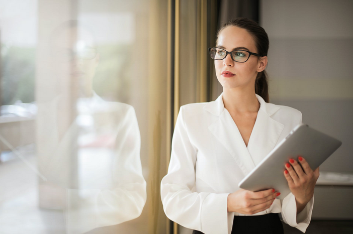 This image shows a female business woman in thought and looking out the window.