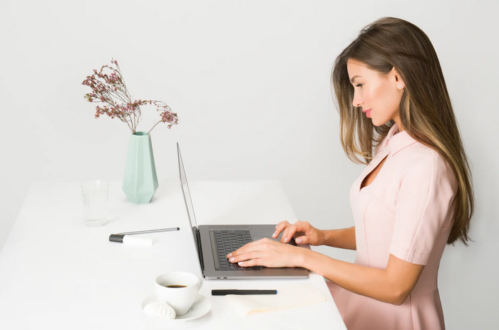 Woman dressed in pink works away on laptop