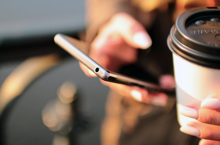 A woman holds onto her black smartphone