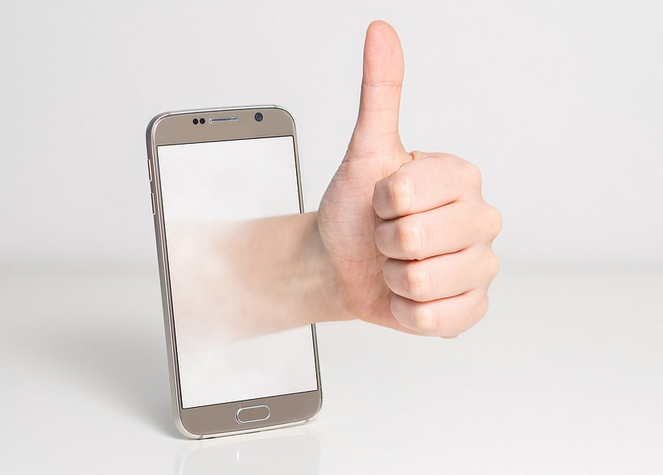 A man giving a thumbs up through his smartphone screen.