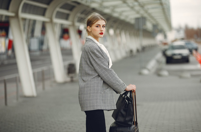The image shows a woman dressed in business attire and with luggage. Hotels might temporarily have to target new segments like business travelers.