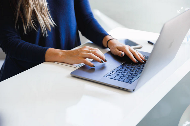 Woman dressed in blue types away on her laptop computer